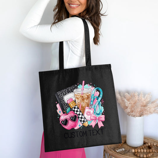 Black tote bag with colorful school supplies graphic and "CUSTOM TEXT".