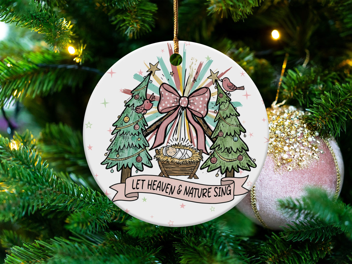 Christmas ornament with nativity scene, two trees, and text "LET HEAVEN & NATURE SING."