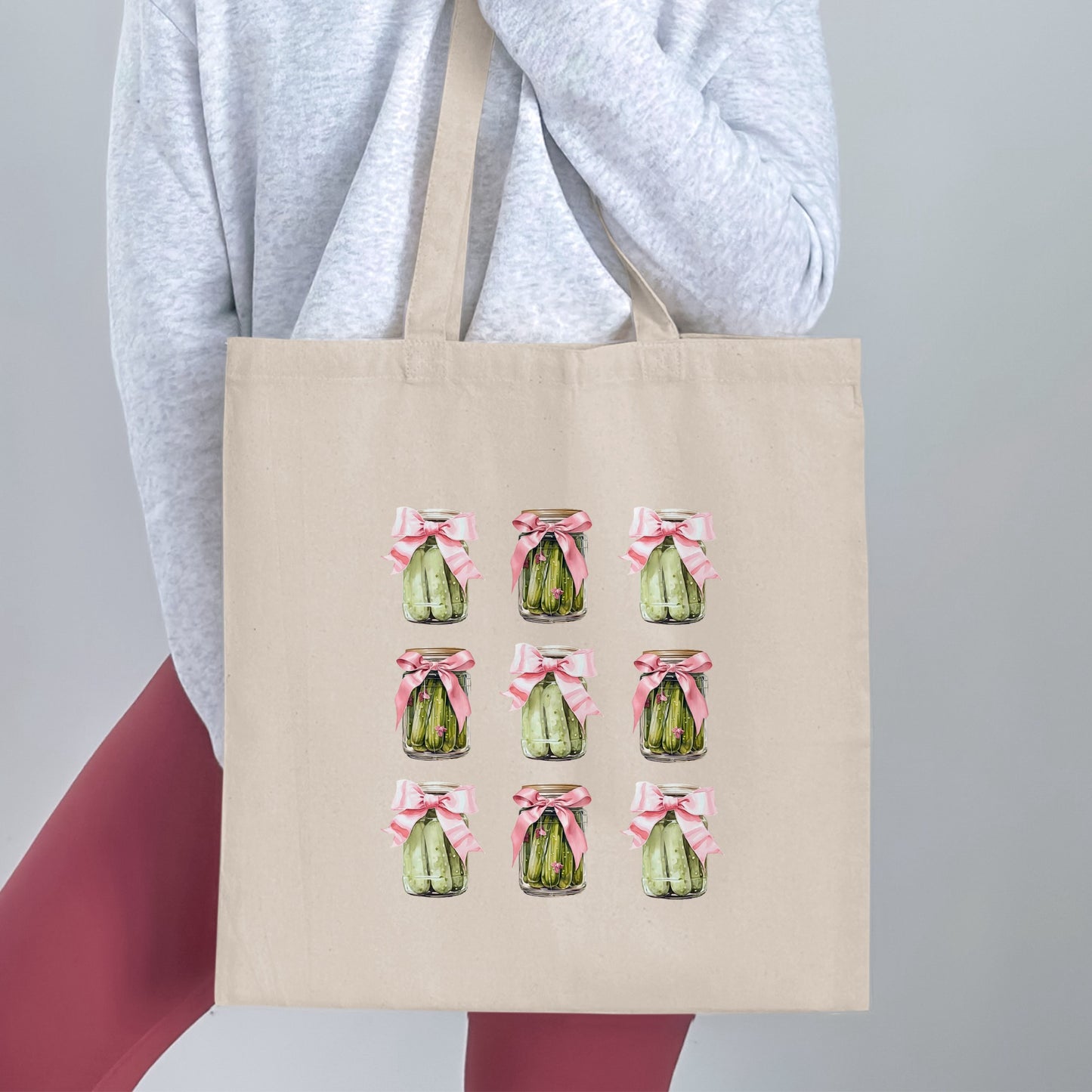 Beige tote bag with nine jars of pickles decorated with pink bows.
