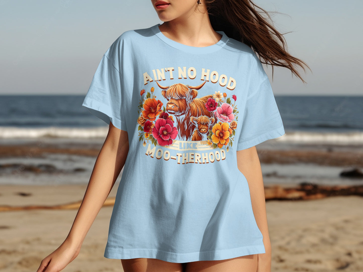 Light blue t-shirt with Highland cow and floral graphic, text "Ain't no hood like moo-therhood".