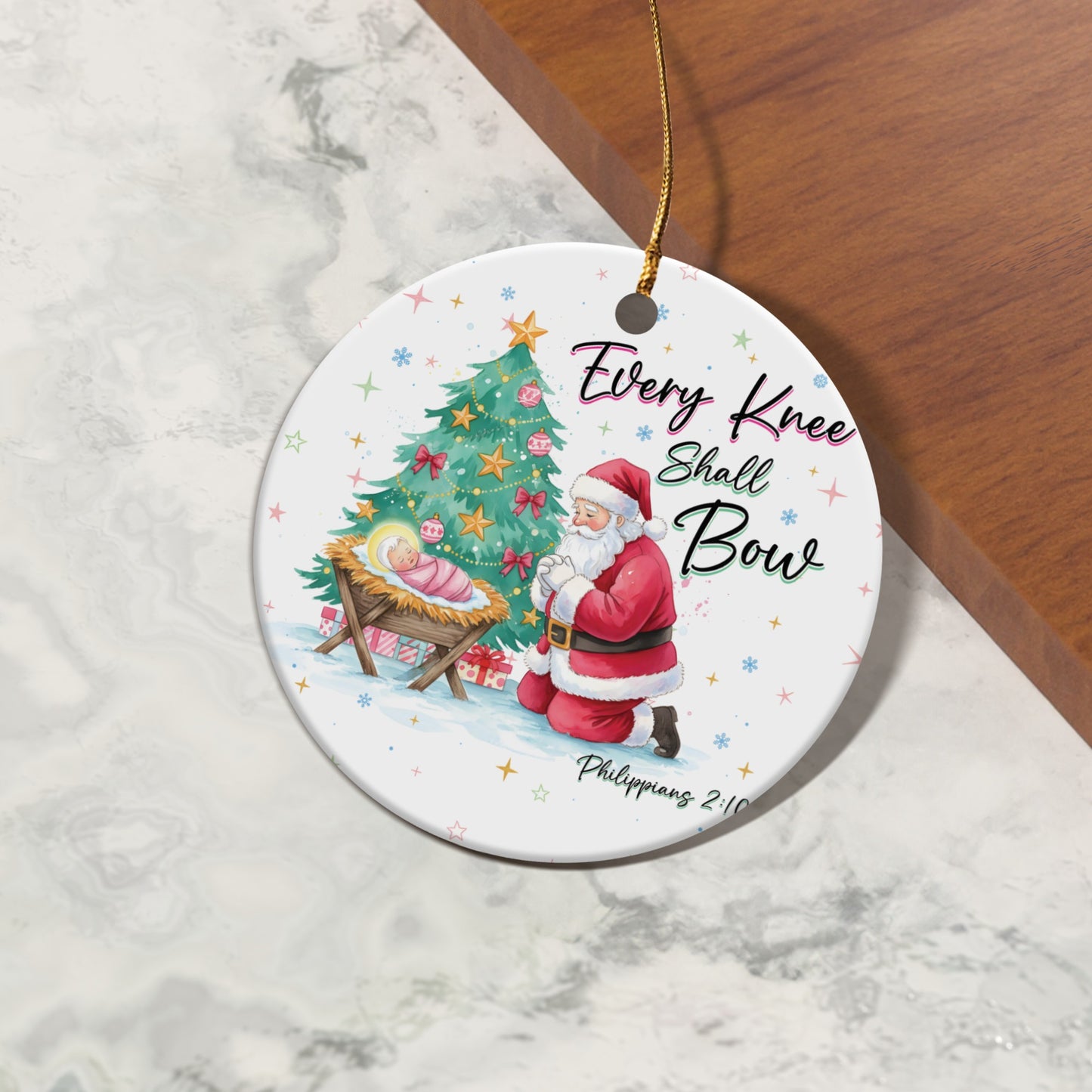 Ornament shows Santa kneeling before Jesus in a manger, with a Christmas tree and text.